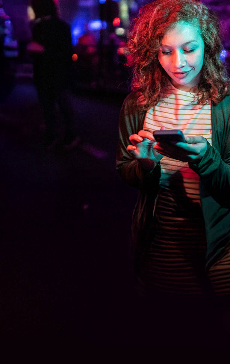 Junge Frau schaut auf ihr Smartphone und nutzt unbegrenztes Datenvolumen.