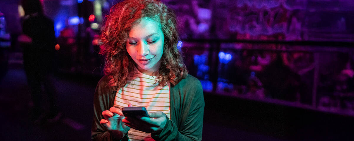 Junge Frau schaut auf ihr Smartphone und nutzt unbegrenztes Datenvolumen.