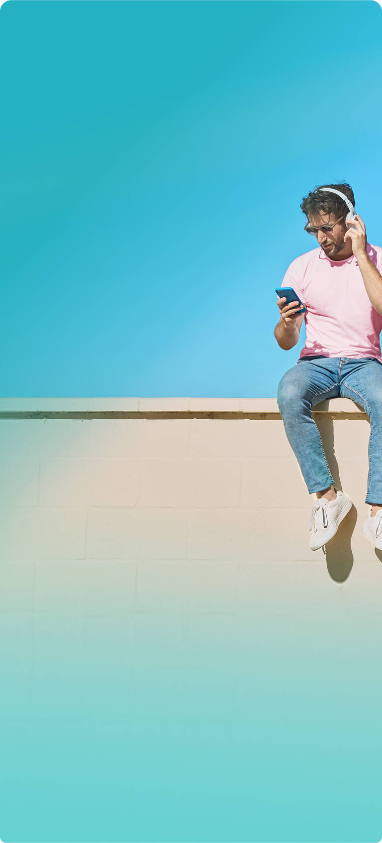 Mann schaut lächelnd auf sein Smartphone und nutzt seinen monatlich kündbaren Handyvertrag mit unbegrenztem Datenvolumen