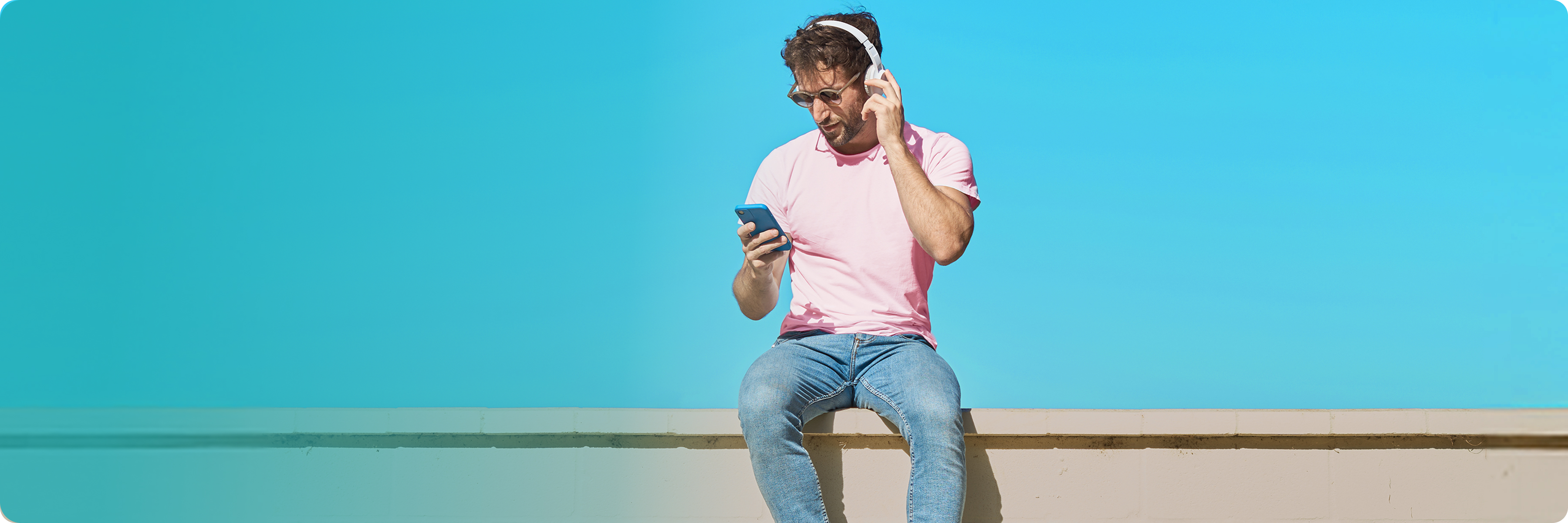 Mann schaut lächelnd auf sein Smartphone und nutzt seinen monatlich kündbaren Handyvertrag mit unbegrenztem Datenvolumen